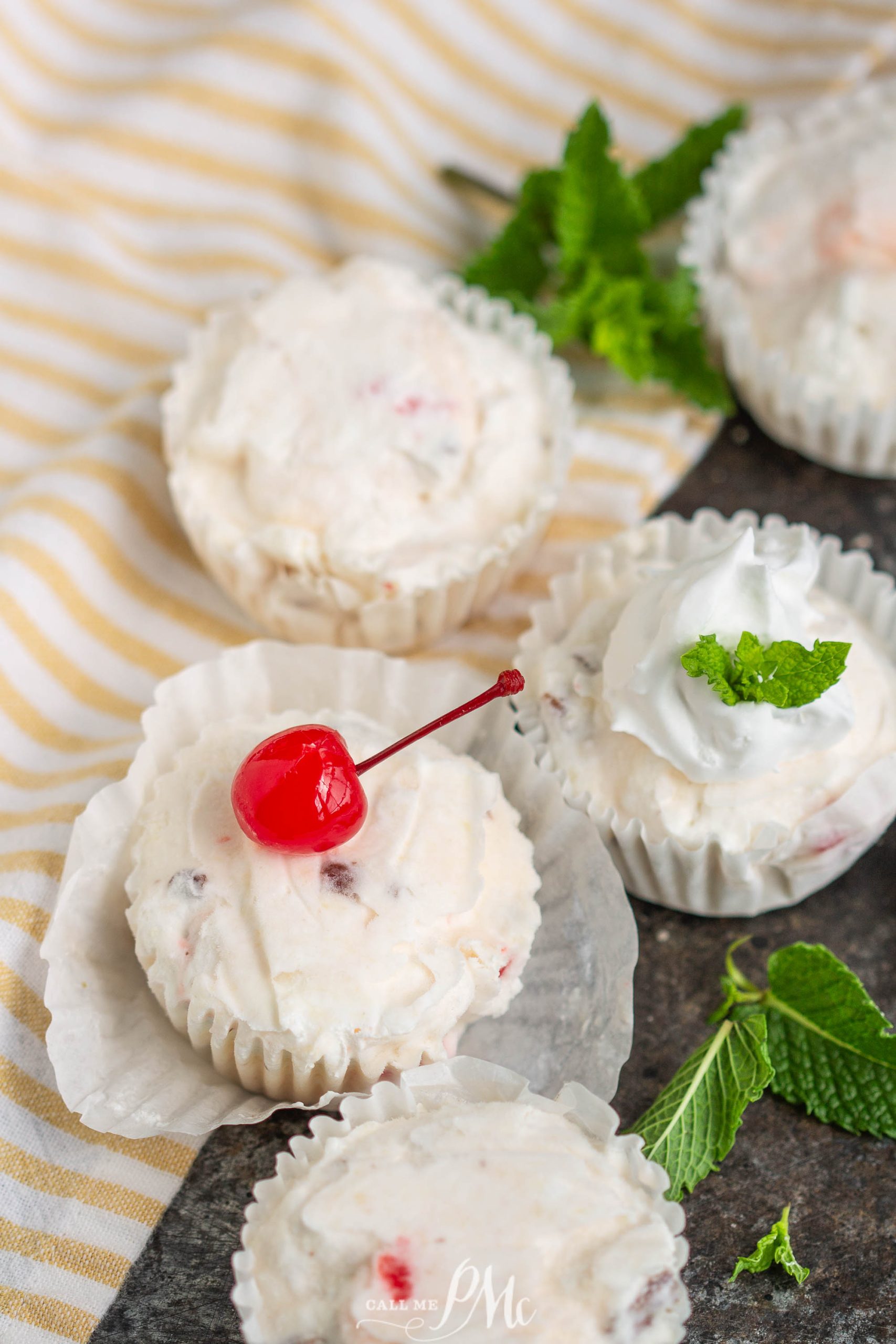 fruit salad cupcakes with cherries and mint leaves on a table.