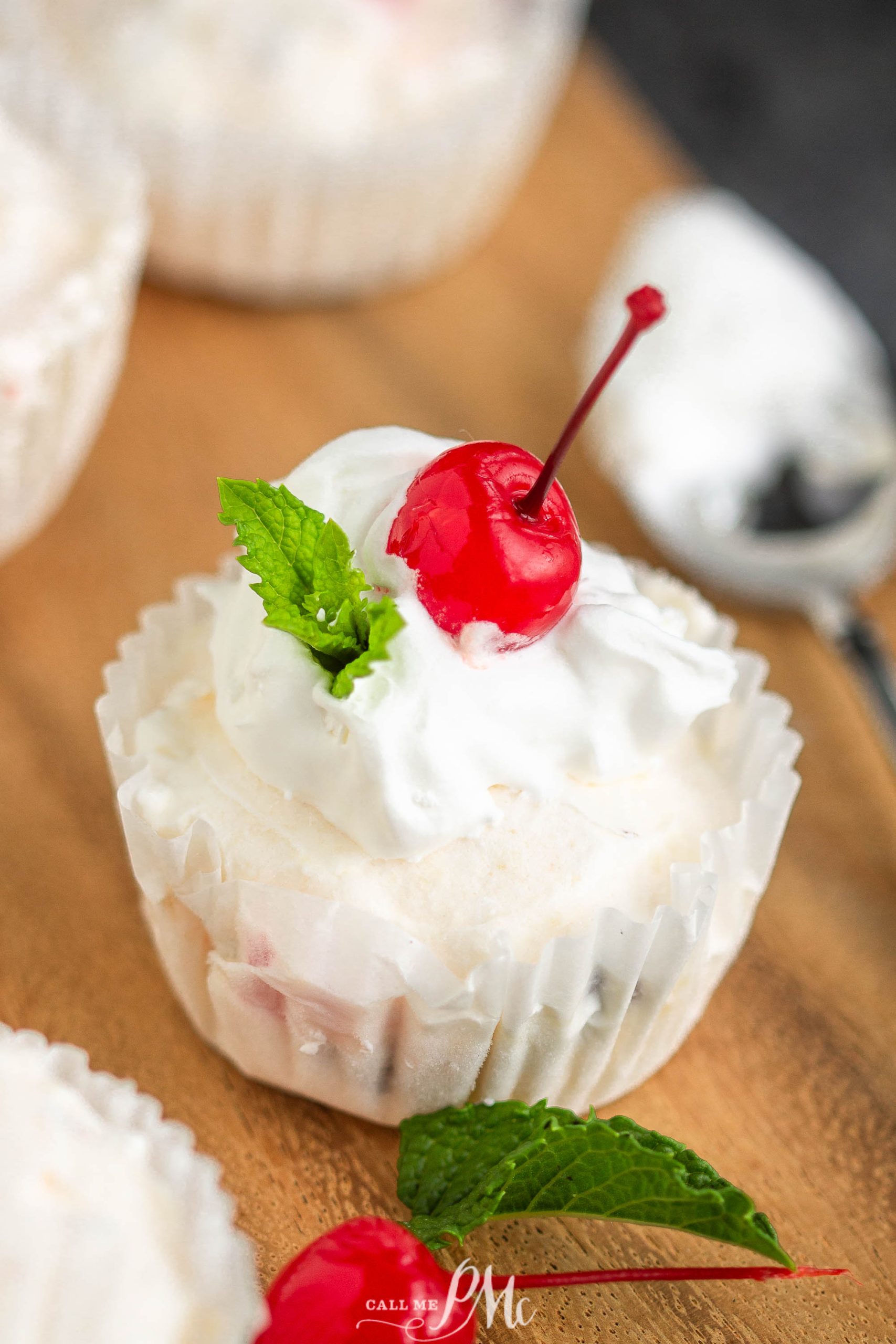whipped cream and cherry cupcakes on a wooden cutting board.
