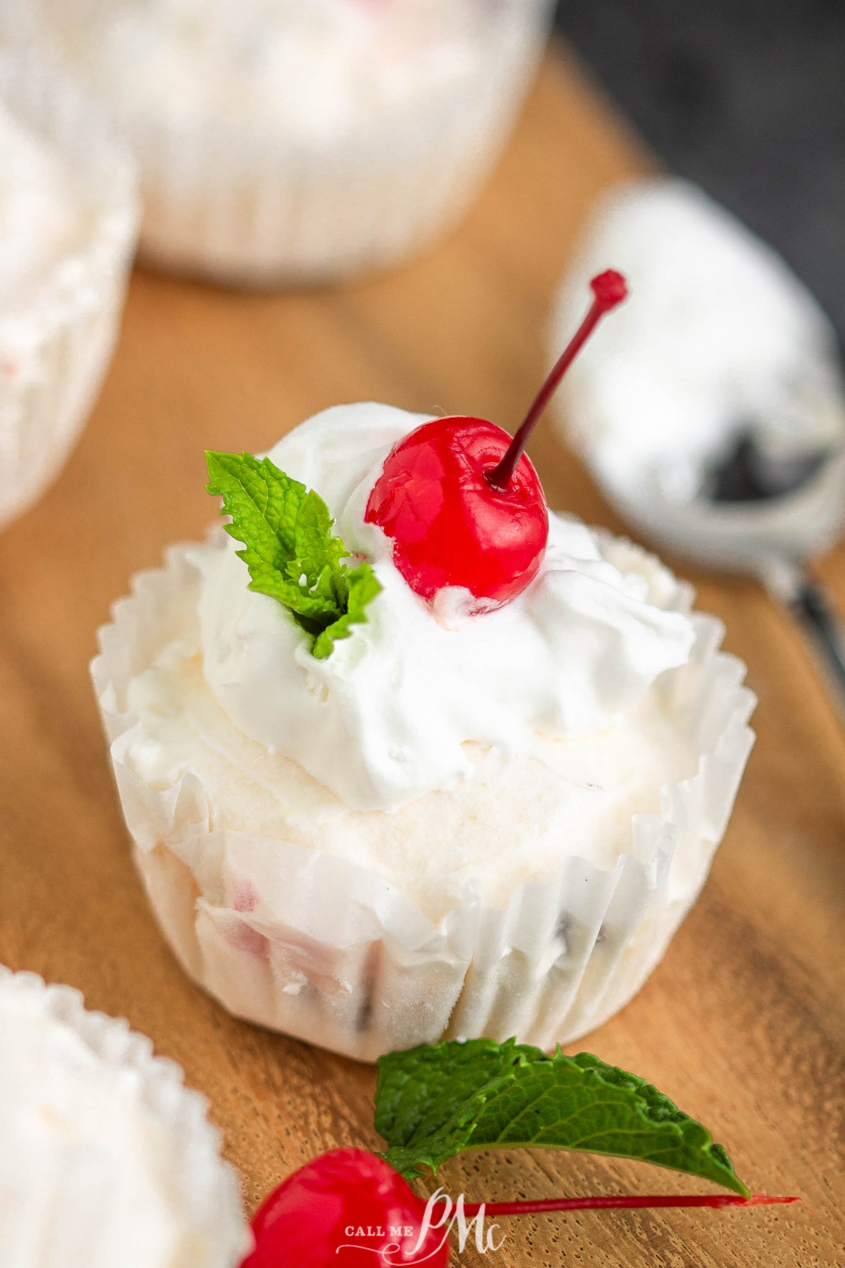 whipped cream and cherry  cupcakes on a wooden cutting board.