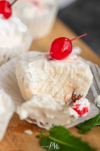 Cherry cheesecake bites with whipped cream and cherries on a plate.