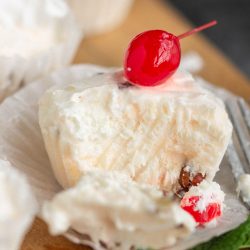 Cherry cheesecake bites with whipped cream and cherries on a plate.