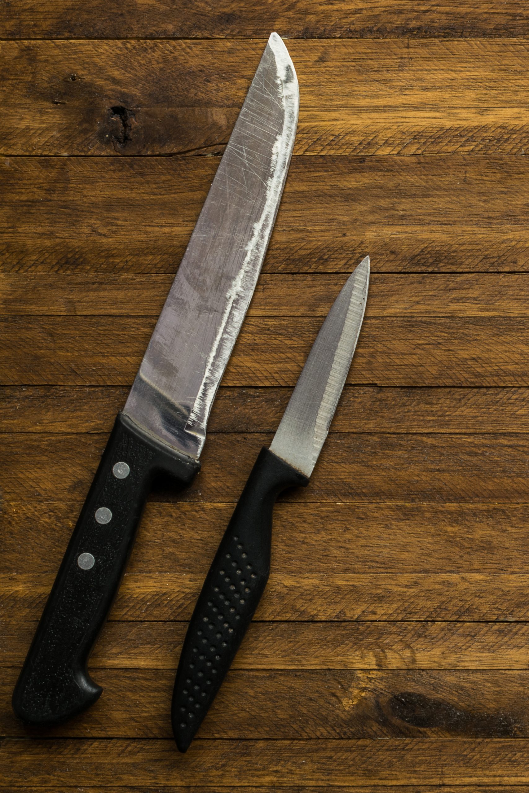 Two knives on a wooden table.