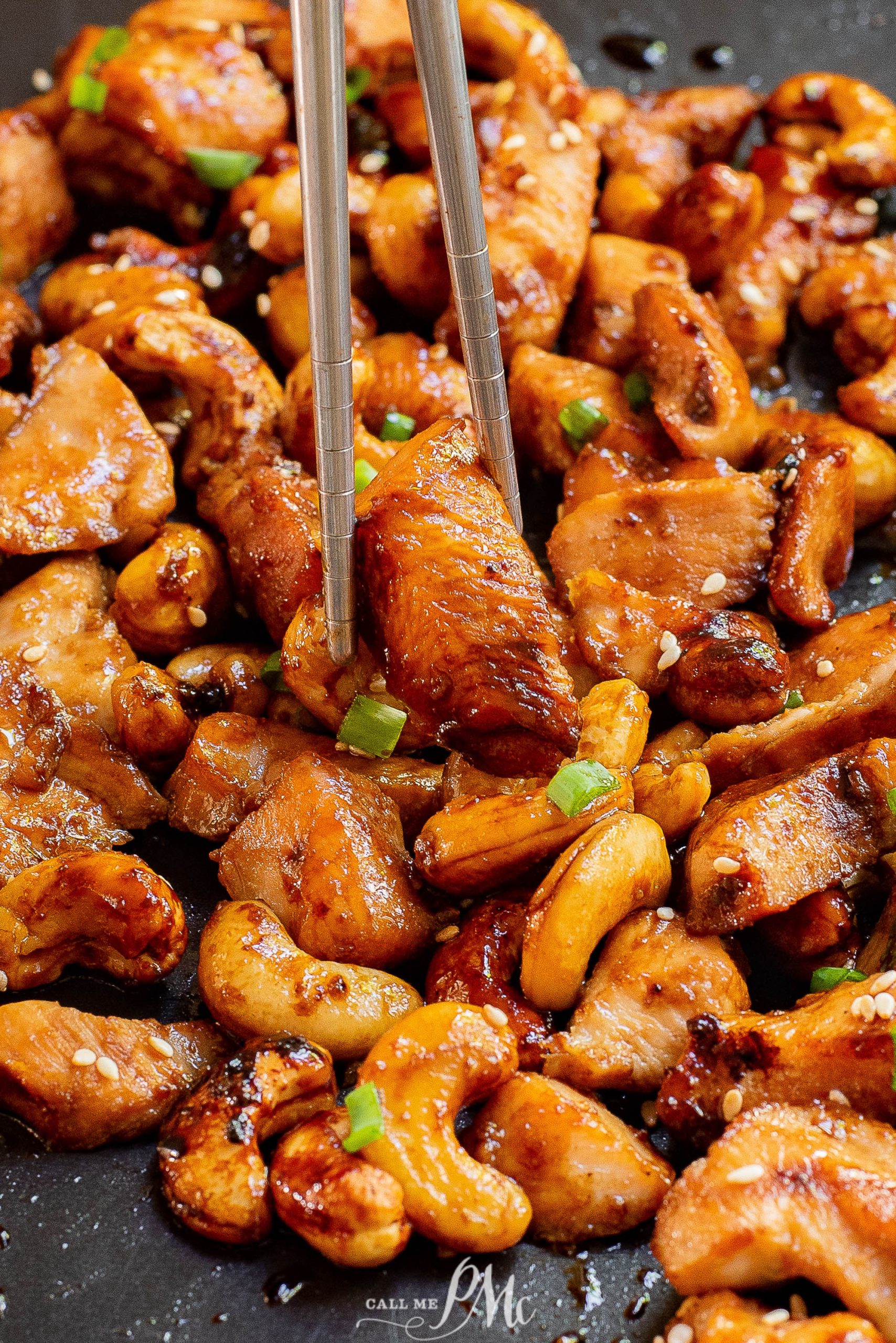 Chicken and cashews on a pan with chopsticks.