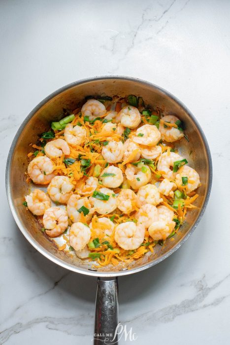 Shrimp in a frying pan on a marble countertop.