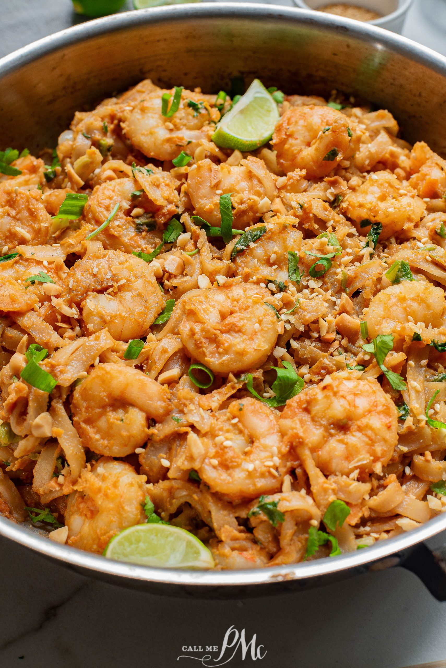 Shrimp and rice in a pan with lime wedges.