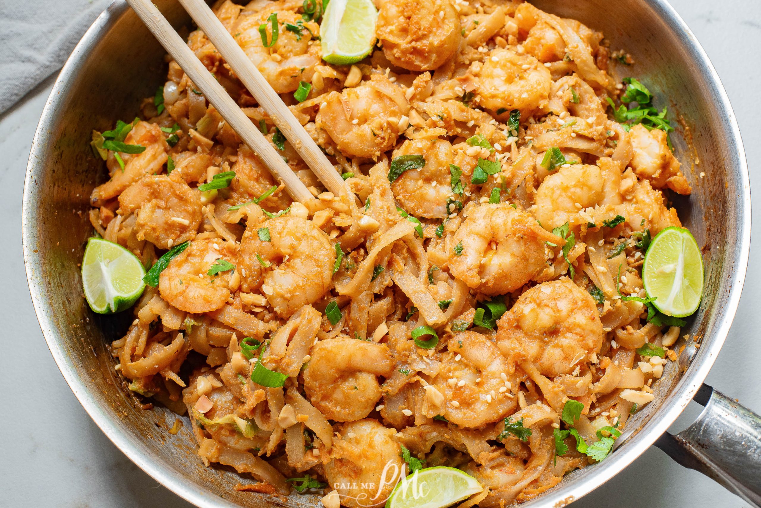 A pan full of shrimp and noodles with chopsticks.