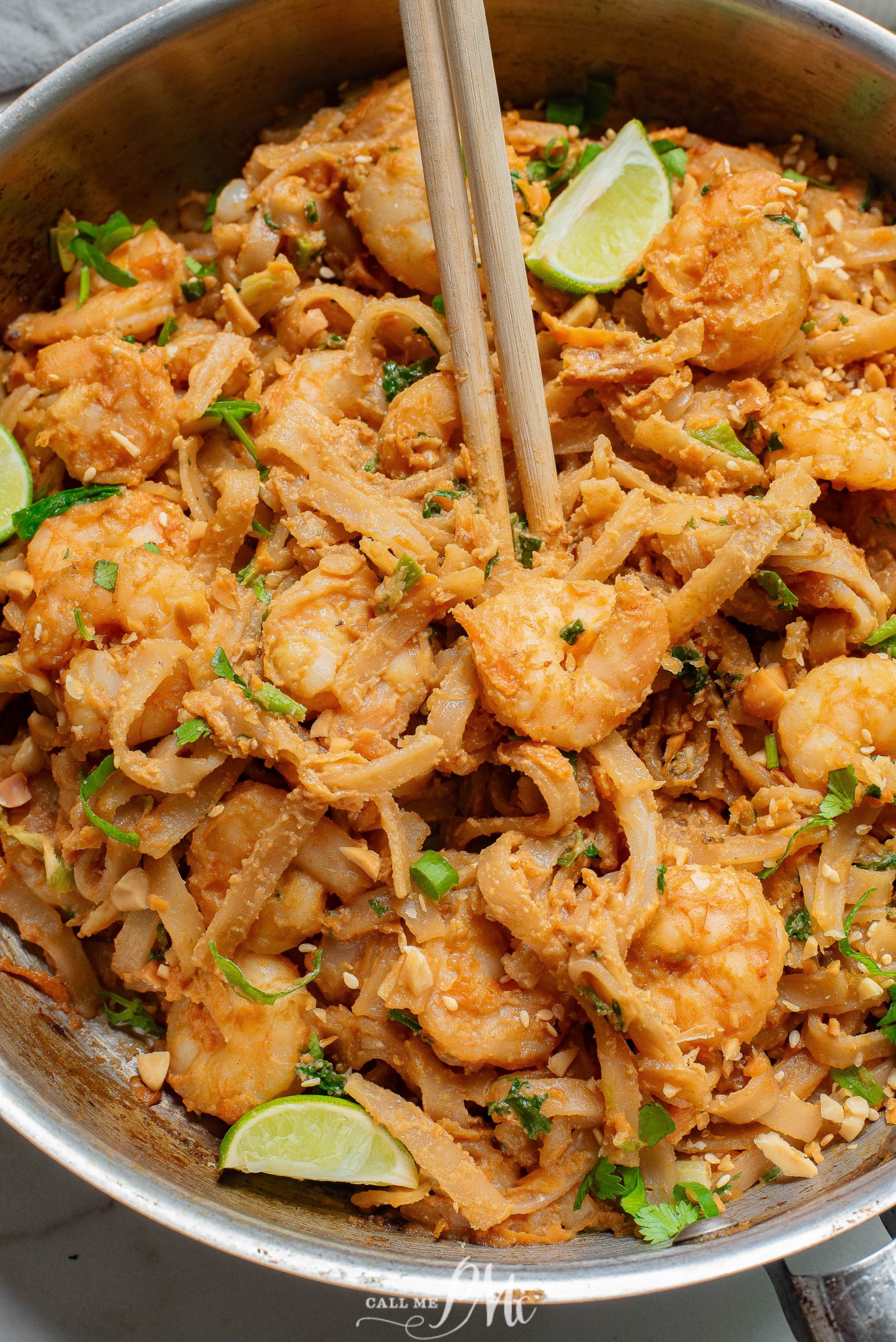 Thai shrimp pad thai in a pan with chopsticks.