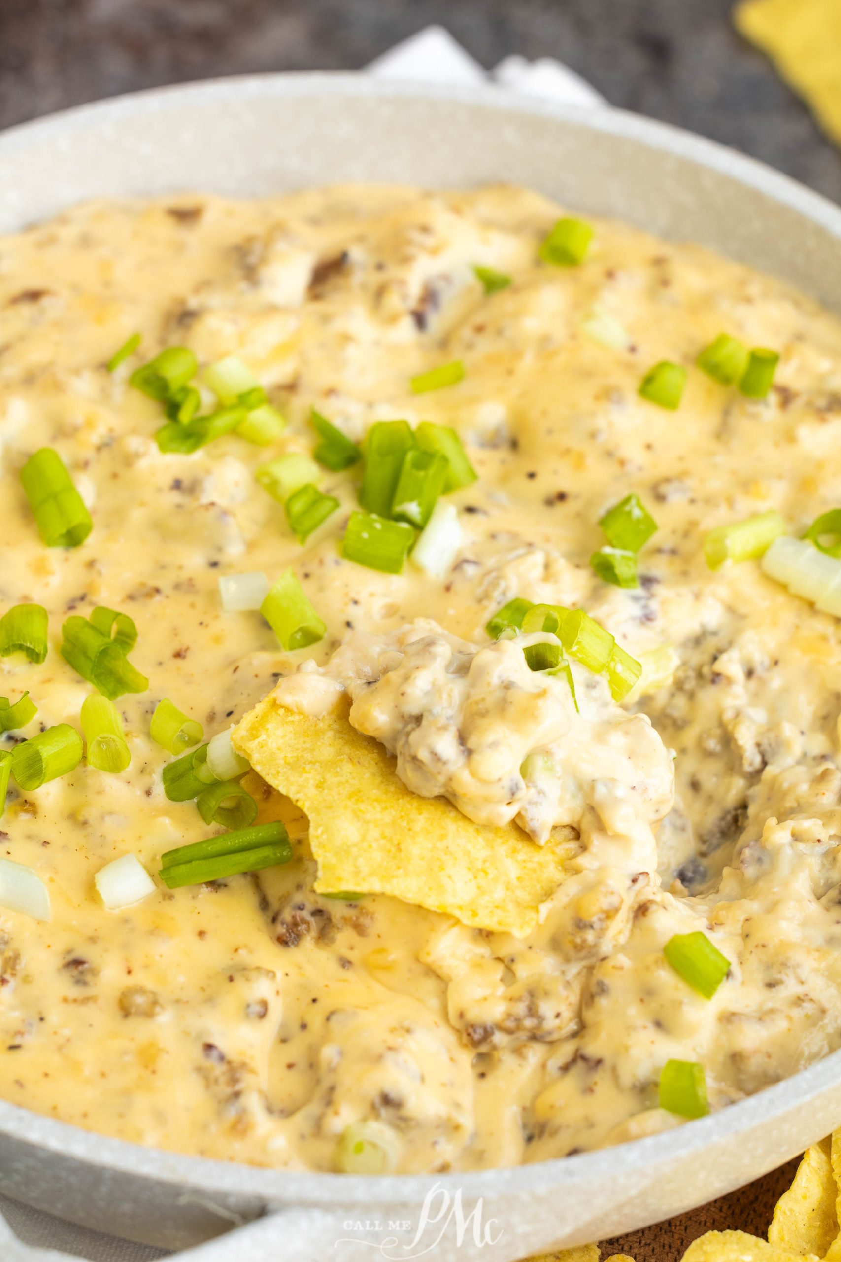 Cheesy nacho dip in a pan with green onions.