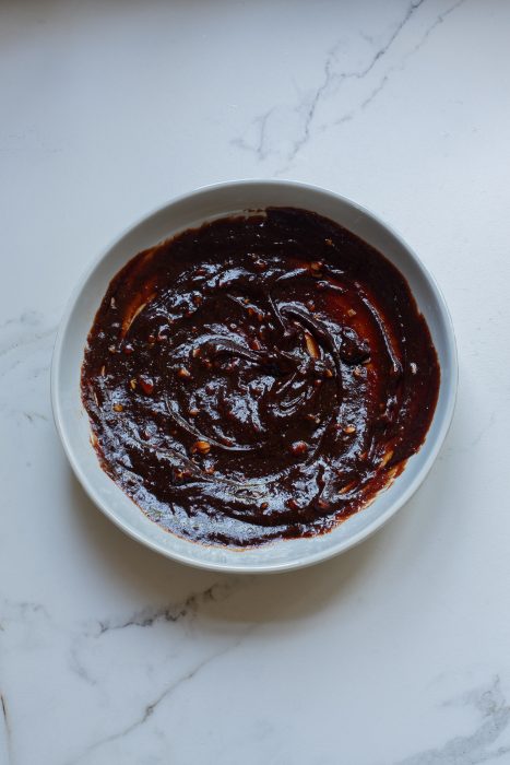 A bowl of  sauce on a marble table.