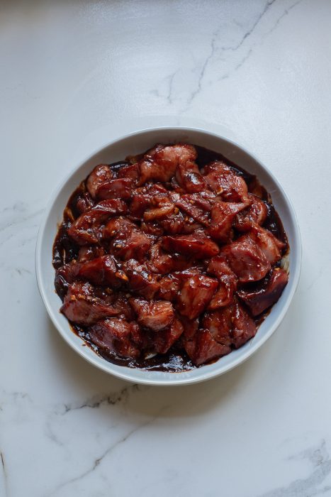 A bowl of meat on a marble counter.