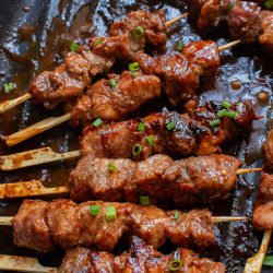 Meat skewers on skewers in a pan.