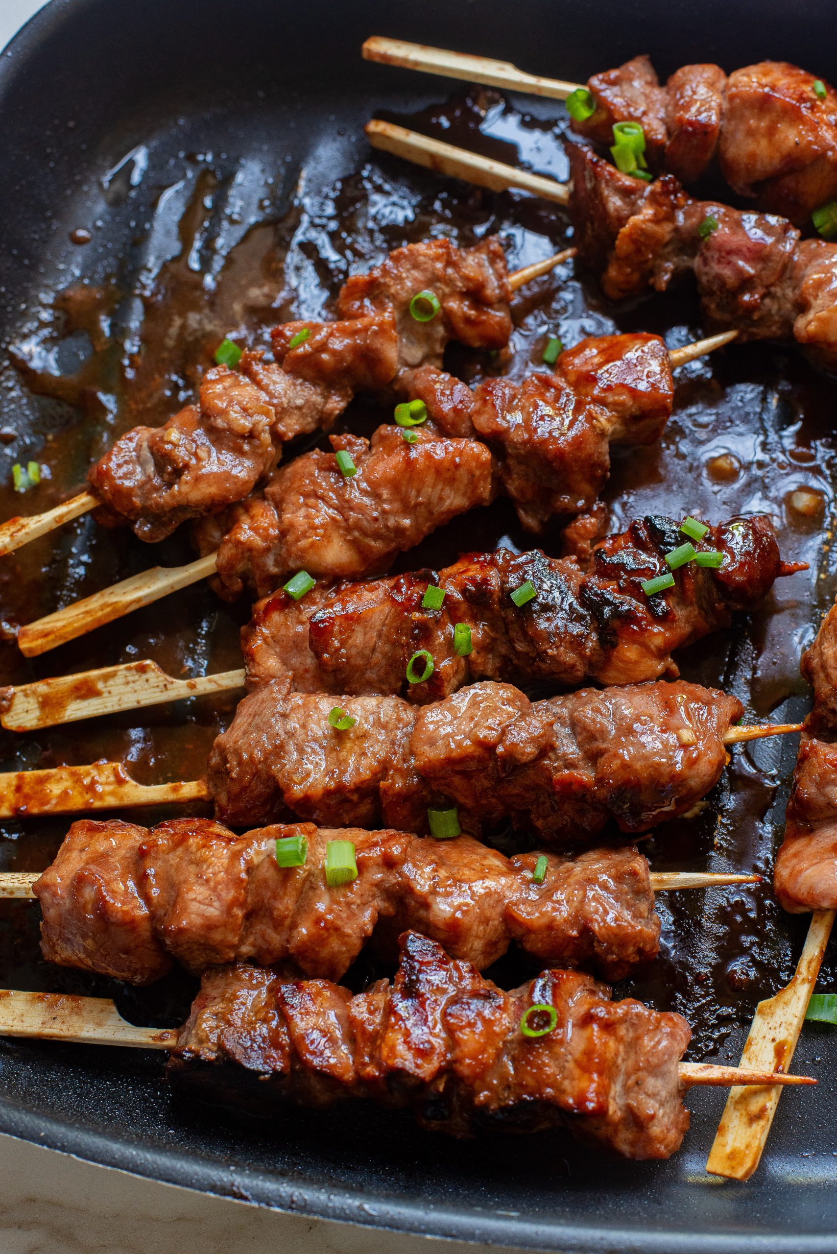 Meat skewers on skewers in a pan.