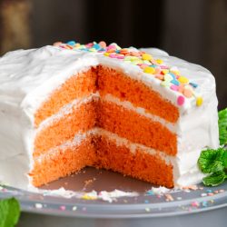 An orange cake with a slice taken out.