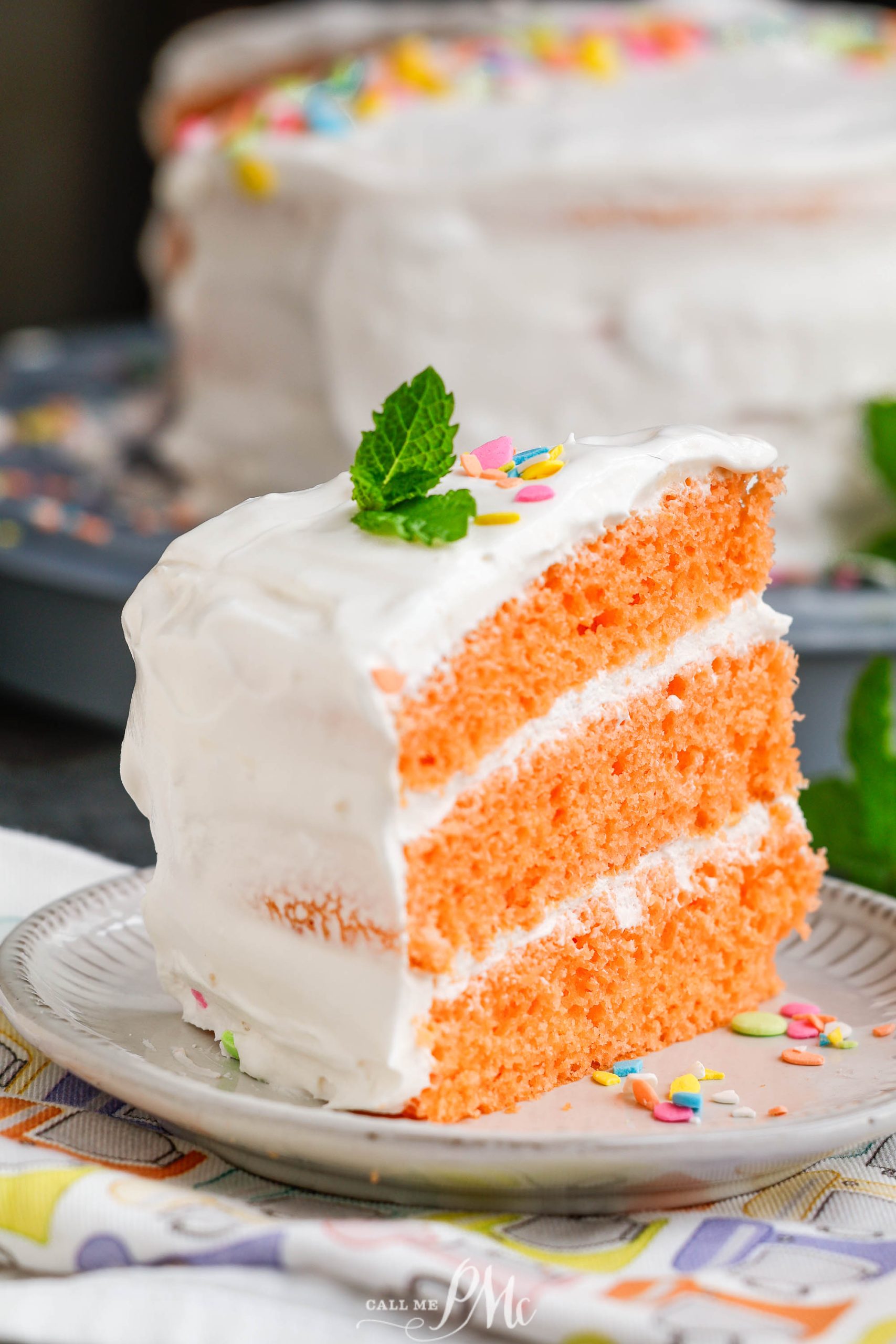 A slice of orange frosted cake on a plate.