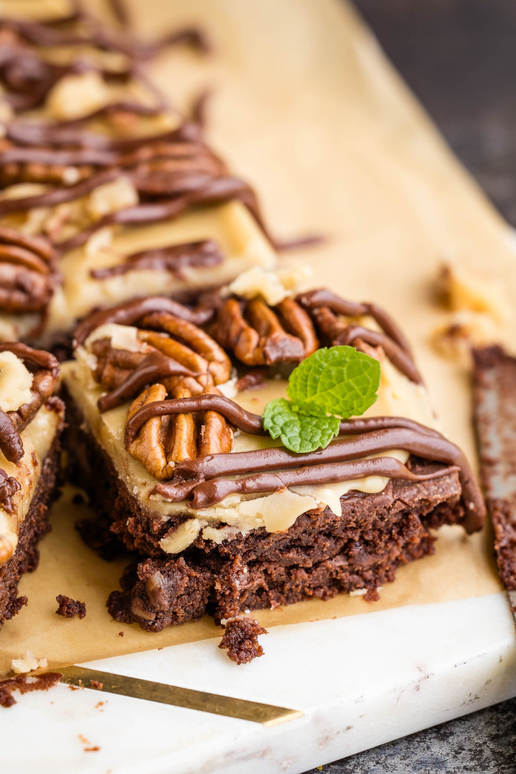 A slice of chocolate praline brownie with pecans and chocolate sauce.