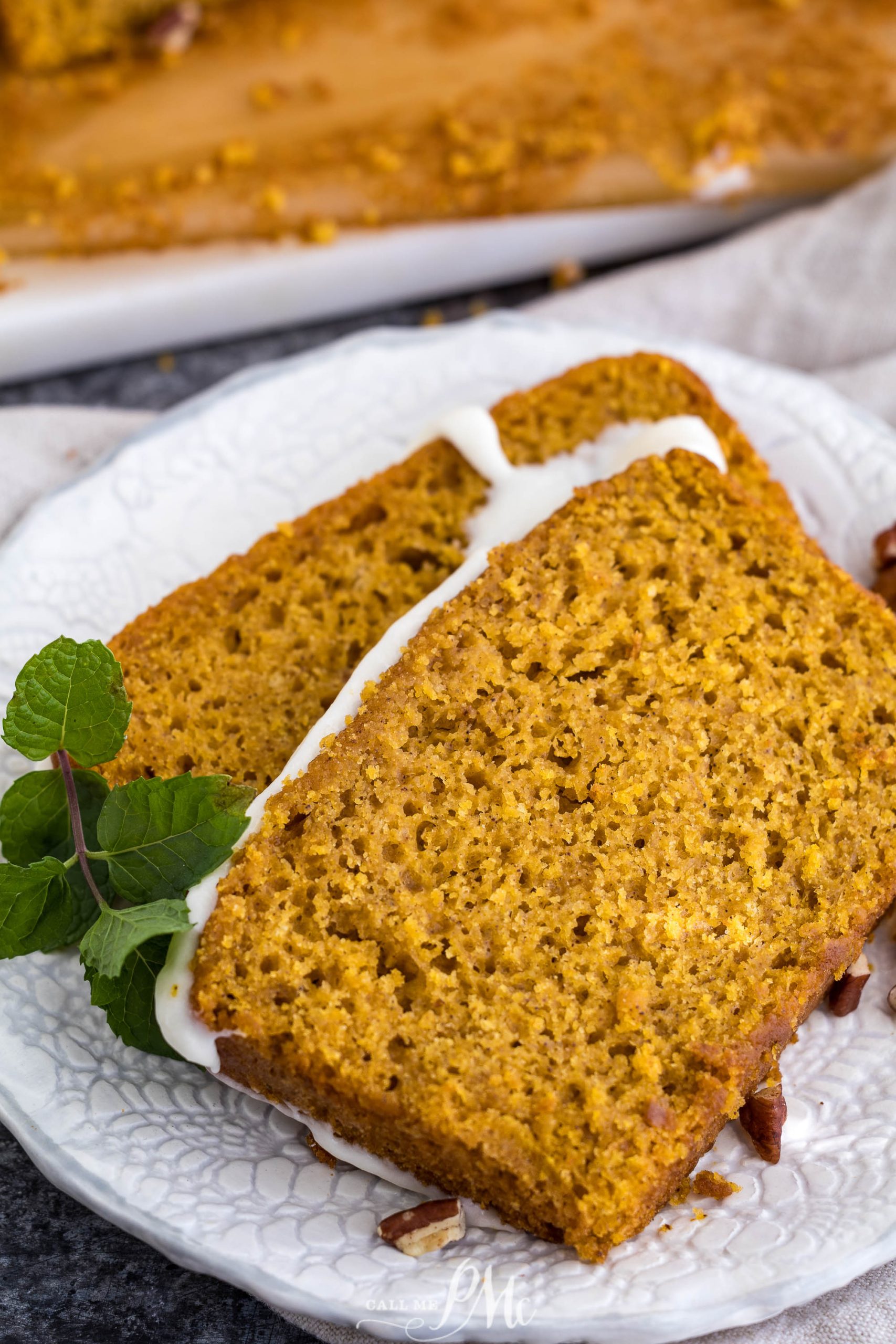 A slice of Pumpkin Loaf with Cream Cheese Glaze on a white plate