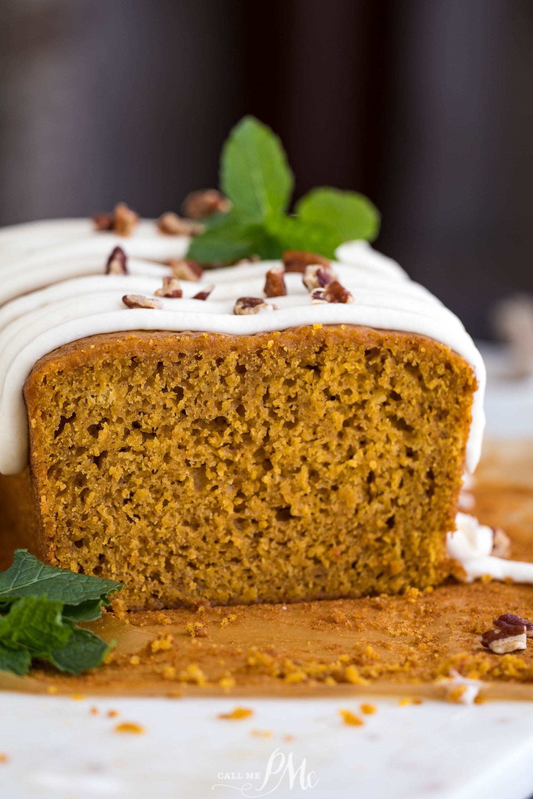 A slice of pumpkin bread with icing and mint leaves
