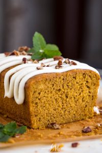 A slice of pumpkin bread with icing and mint leaves