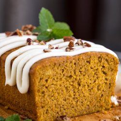 A slice of pumpkin bread with icing and mint leaves