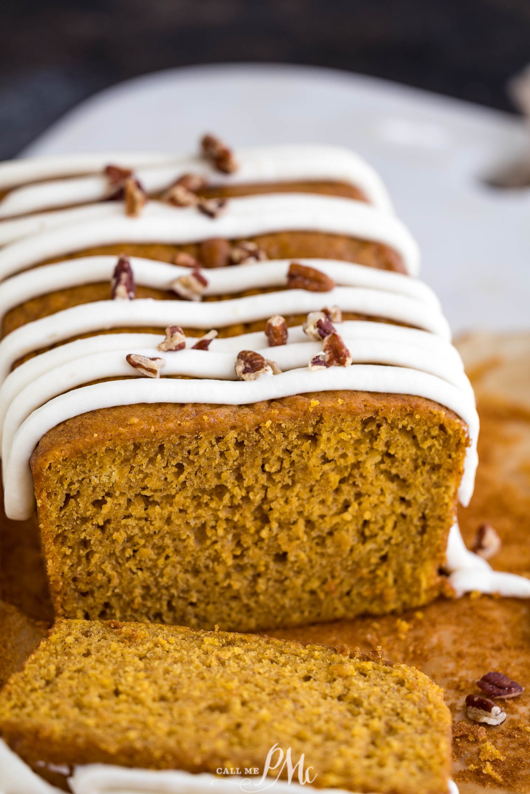 A slice of pumpkin bread with icing and pecans