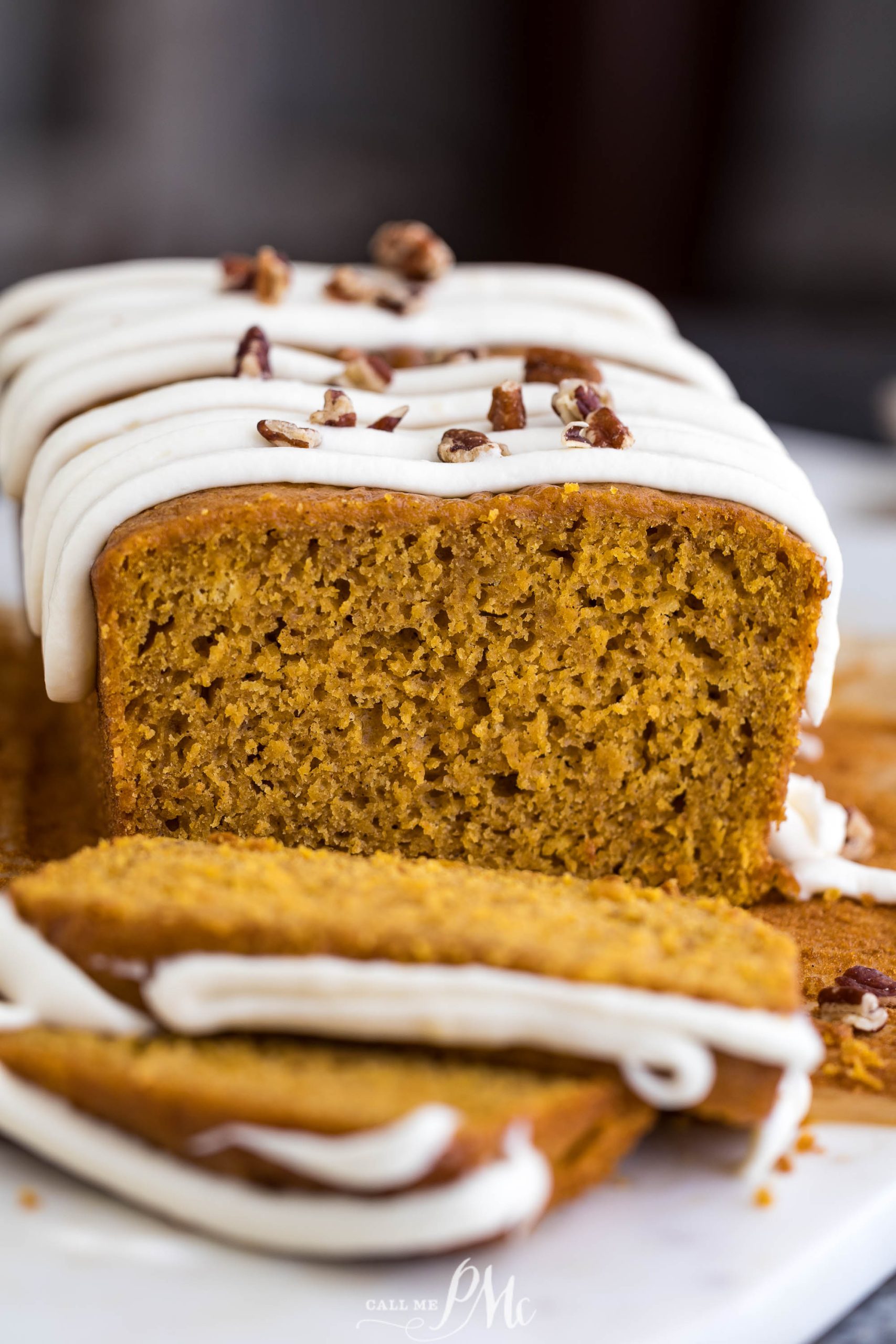 A slice of pumpkin bread with icing and pecans