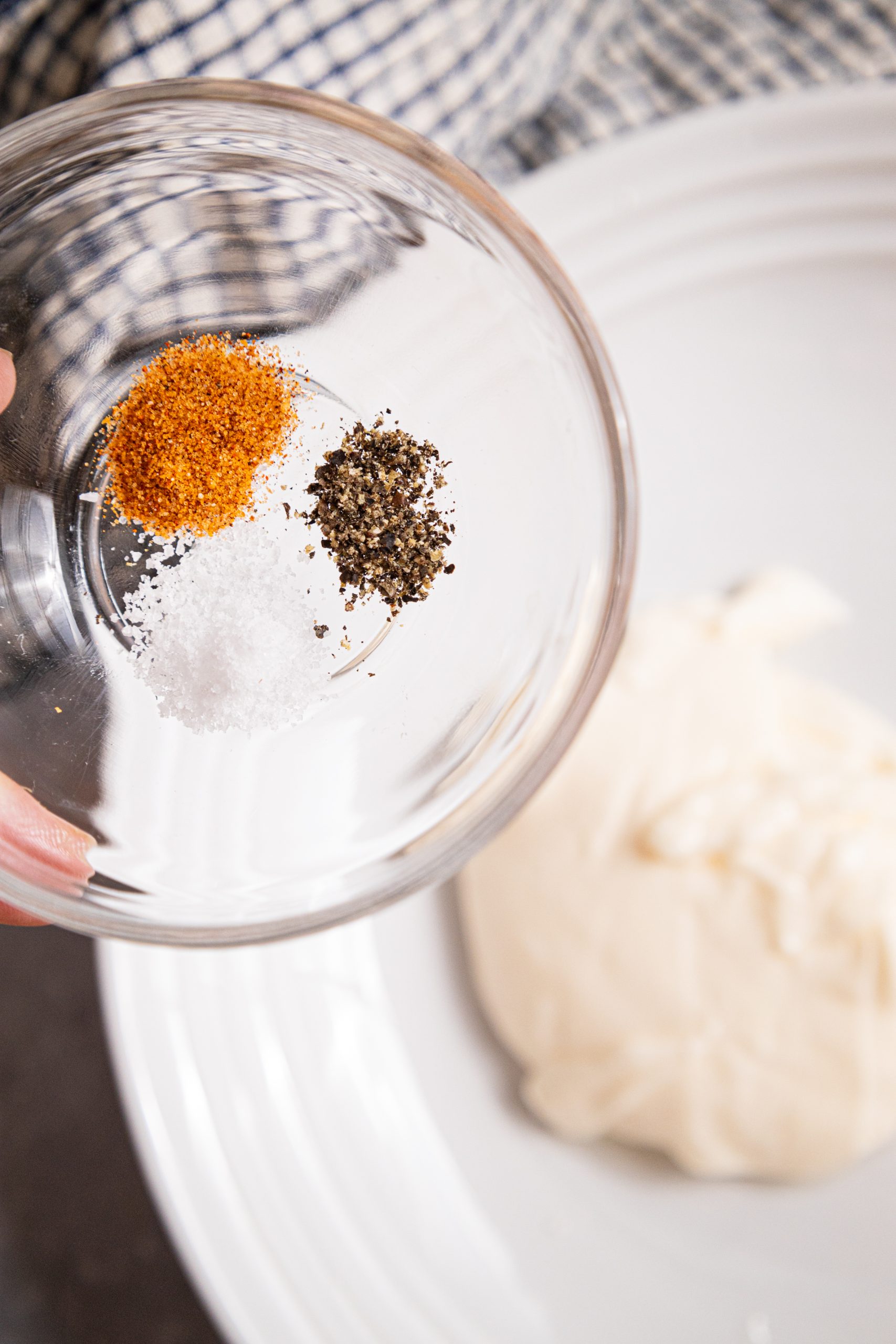 A person is putting spices into a bowl.