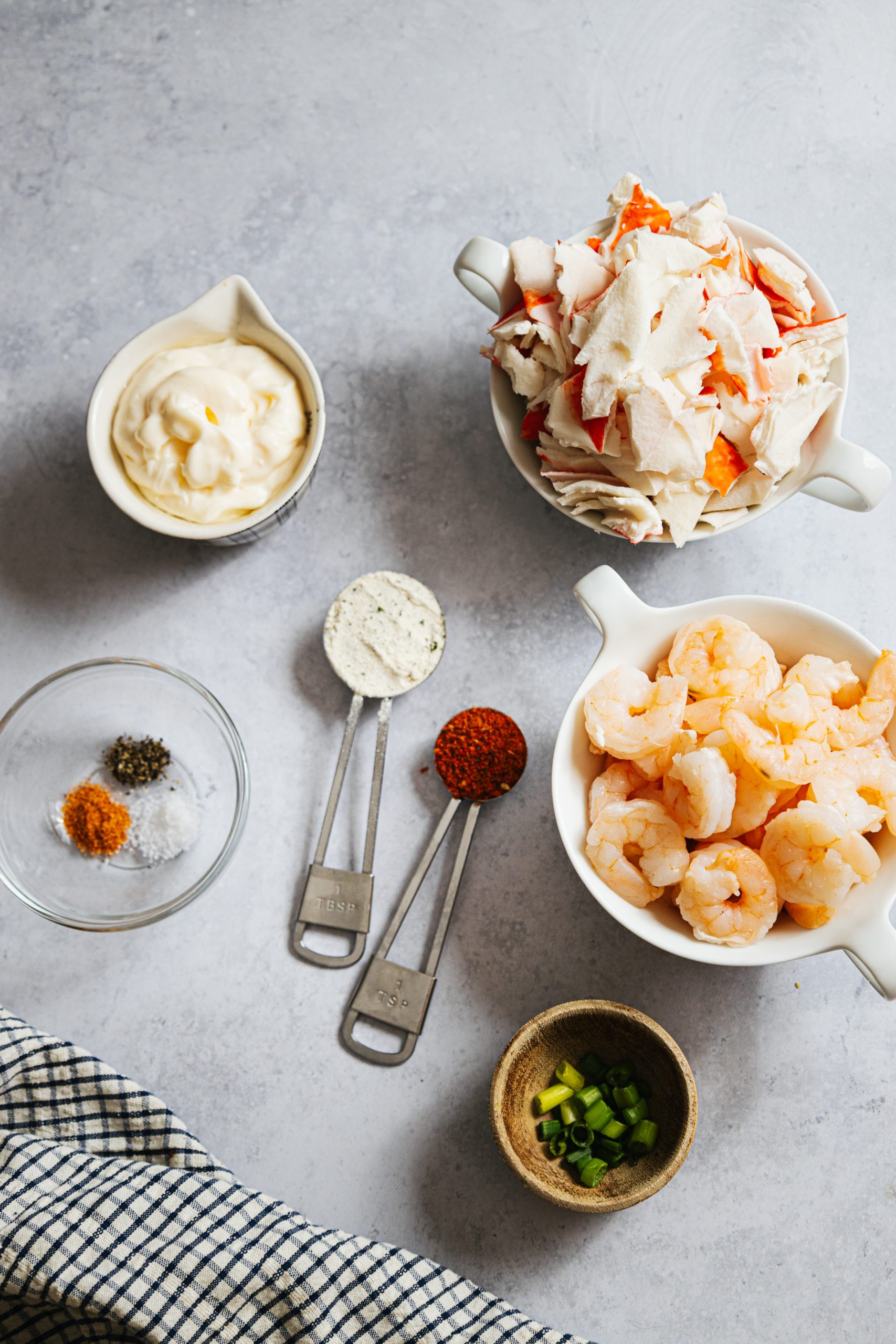 A bowl of shrimp, sour cream, and other ingredients on a table.