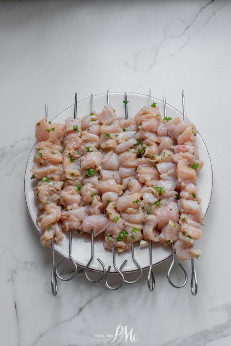 Chicken skewers on skewers on a white plate.