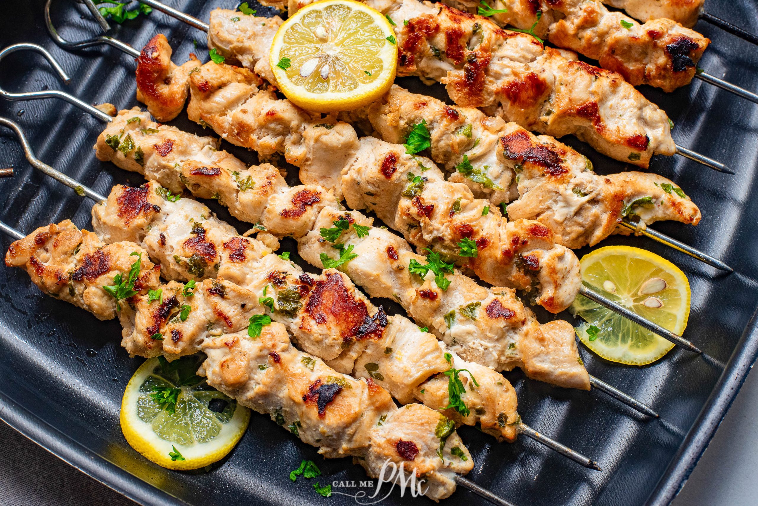 Chicken skewers with lemon wedges on skewers.