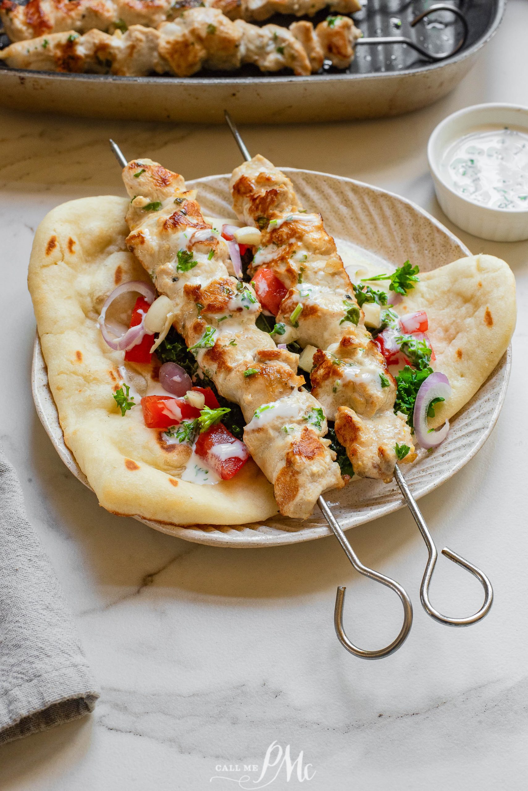Chicken skewers on a plate with tzatziki sauce.