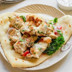 Chicken Souvlaki with Naan on a plate with tzatziki sauce.