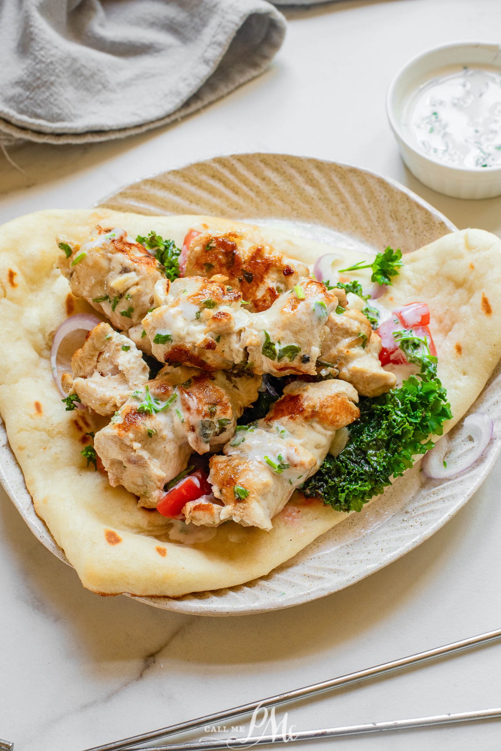 Chicken Souvlaki with Naan on a plate with tzatziki sauce.