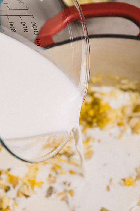 A pot of milk being poured into a pan.