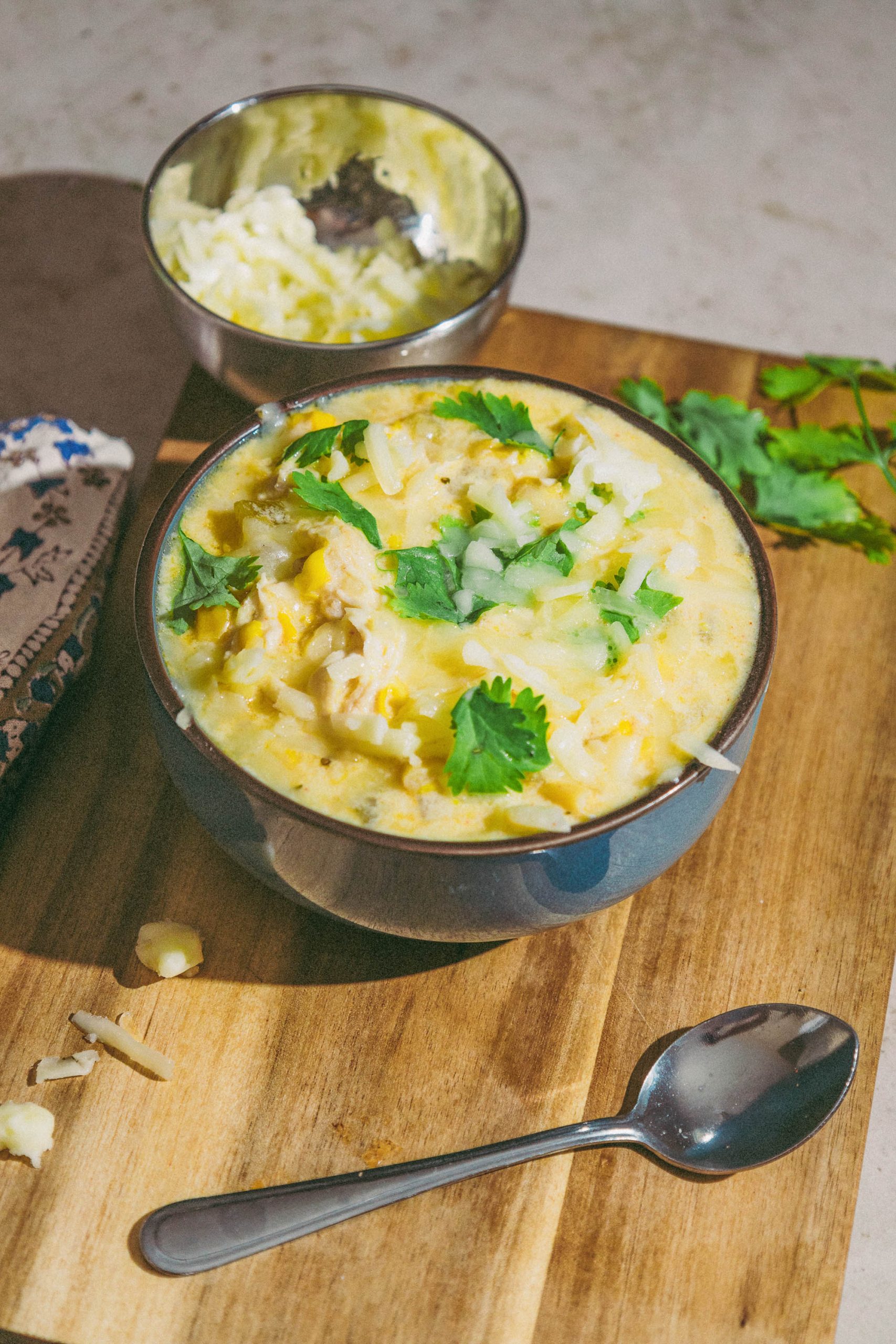 A bowl Green Chili Chicken Corn Chowder on a wooden cutting board.