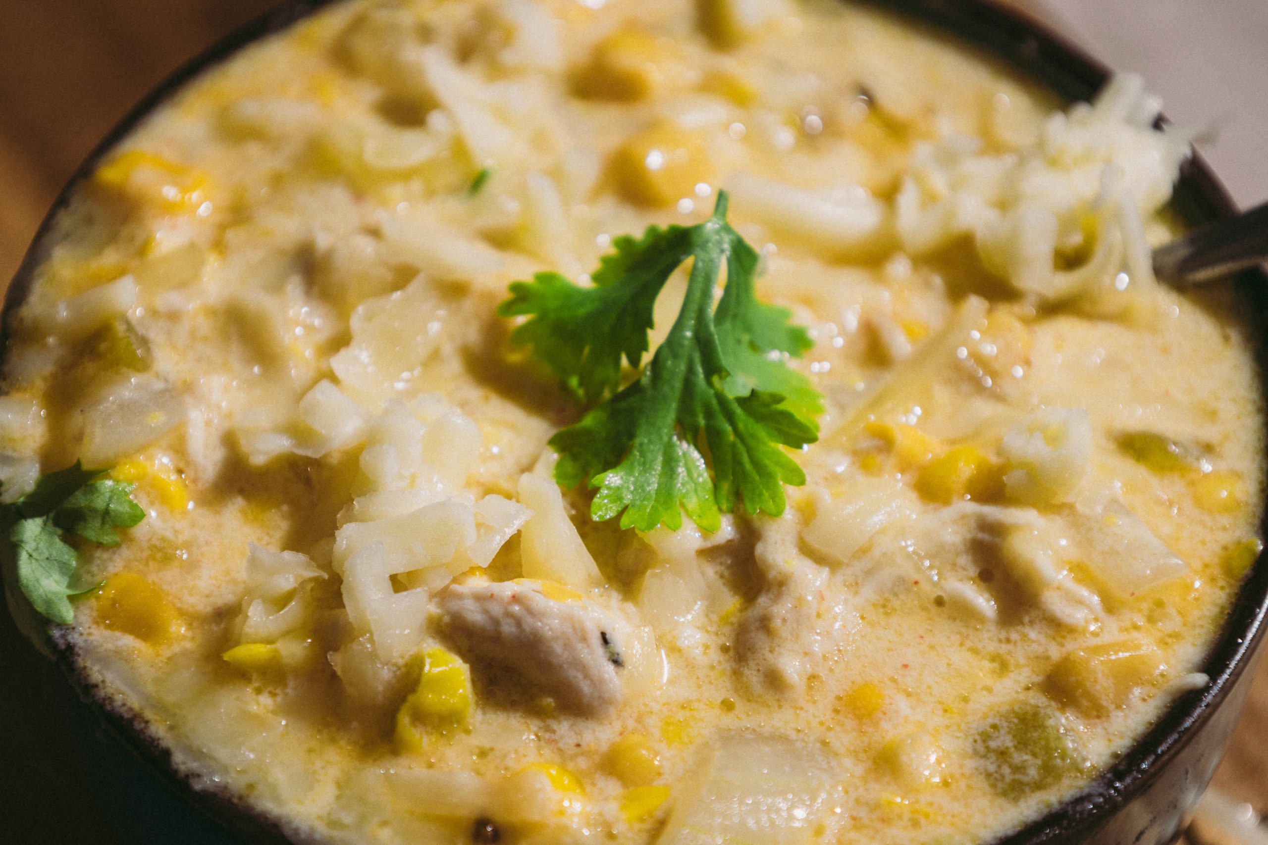A bowl of Green Chili Chicken Corn Chowderwith a spoon.