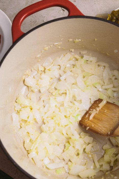 Sauteing onions in a pan with a wooden spoon.