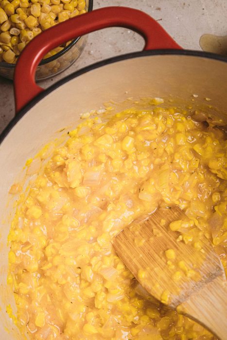 A pot of corn with a wooden spoon in it.