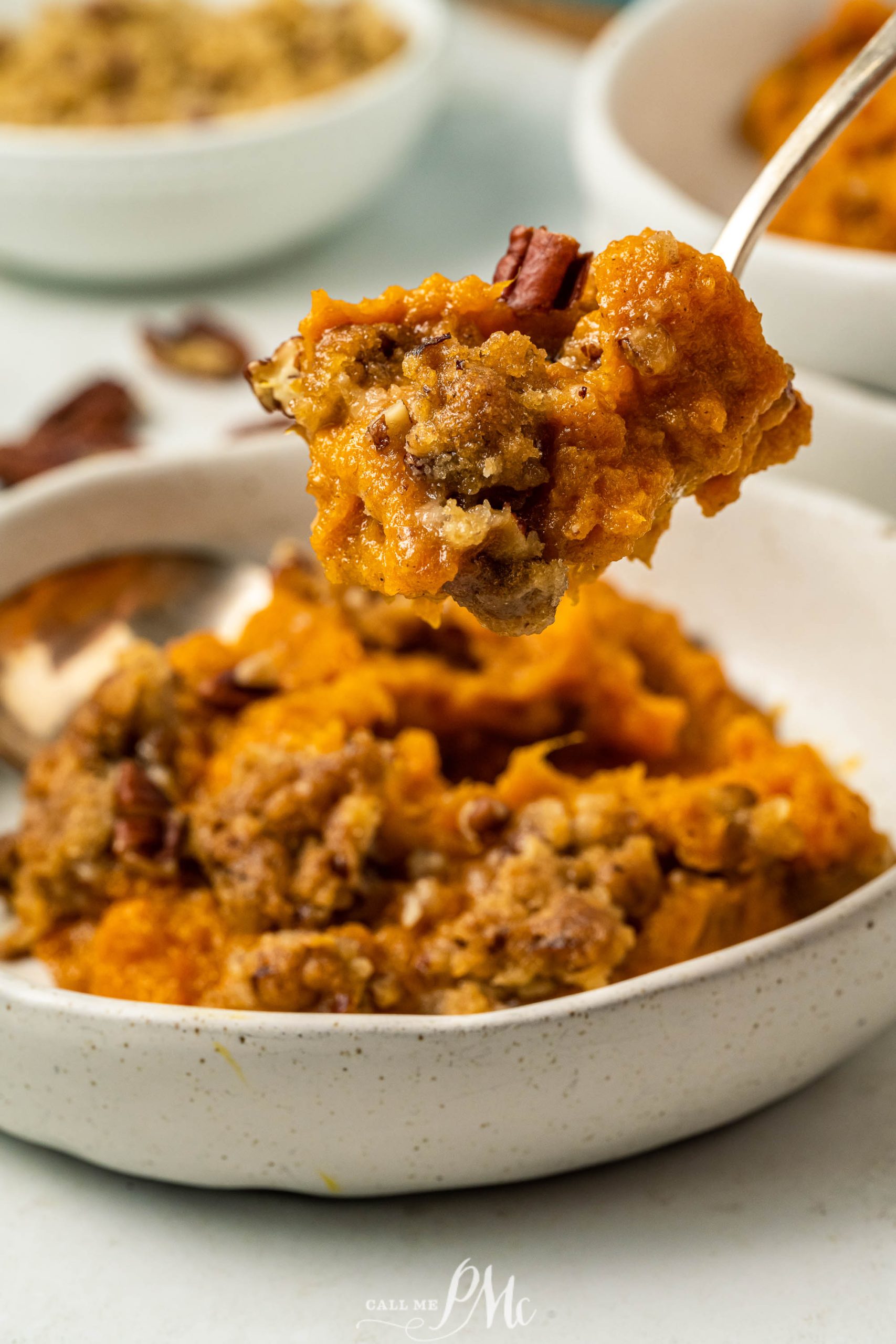 A spoonful of sweet potato casserole in a white bowl.