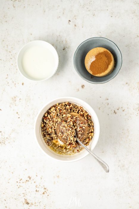 A bowl of oatmeal with granola and a spoon next to it.