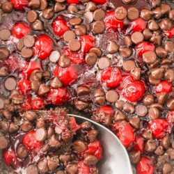 A spoonful of cherry chocolate chip cookie dough in a baking dish.