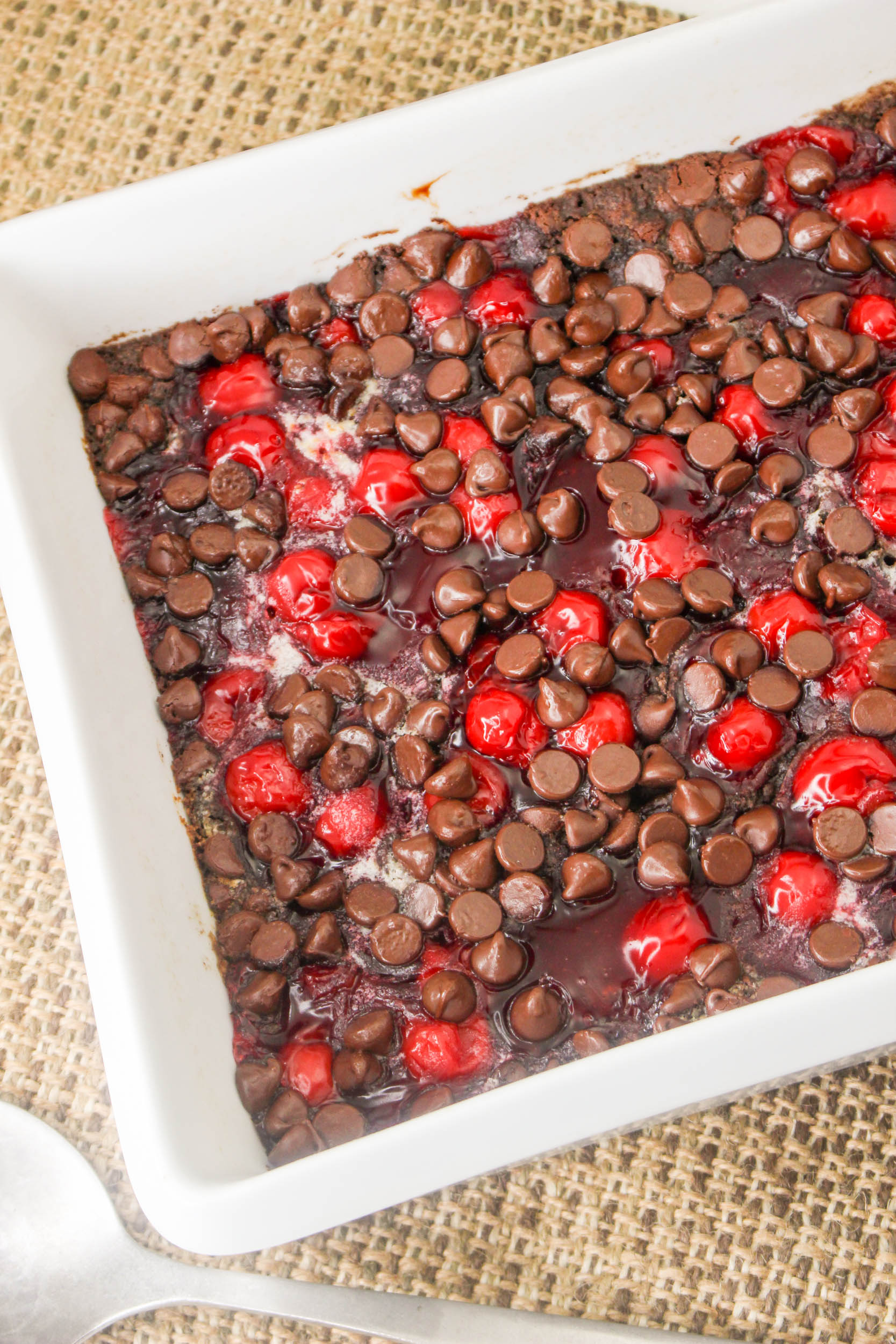 A dish with chocolate chips and cherries in it.