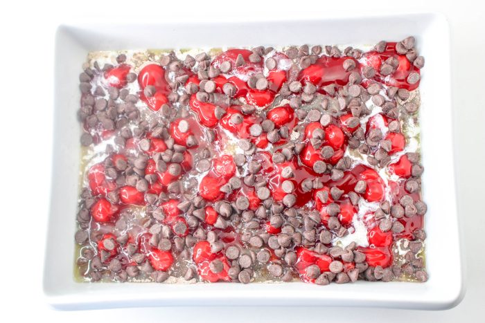 A square dish filled with chocolate chips and cherries.