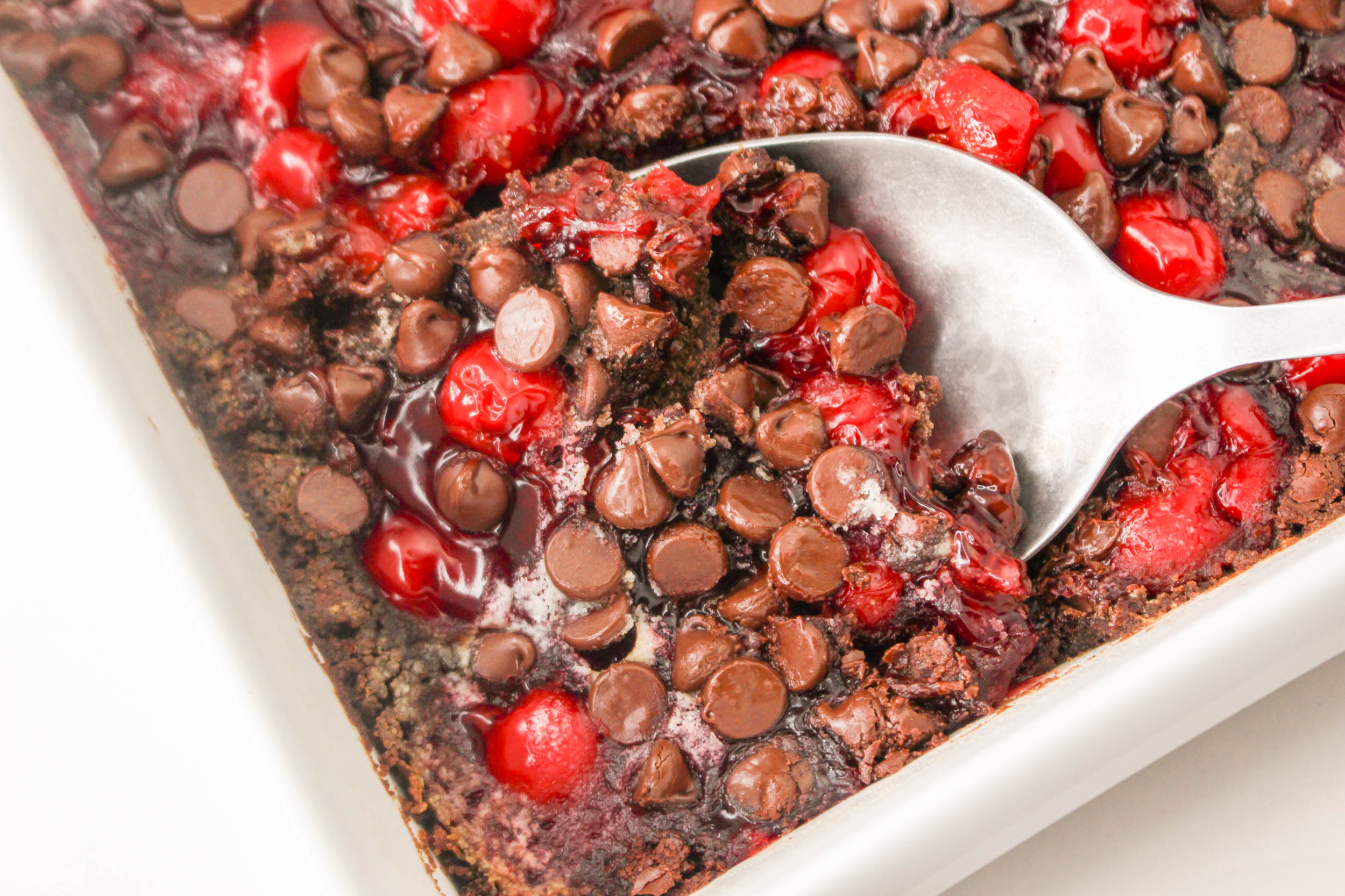 A dish with chocolate chips and cherries in it.