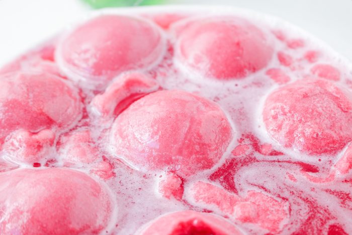 A close up of pink ice cream balls in a bowl.