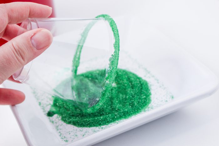 A person pouring green glitter into a bowl.