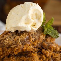 A plate of pumpkin cobbler with ice cream on top.
