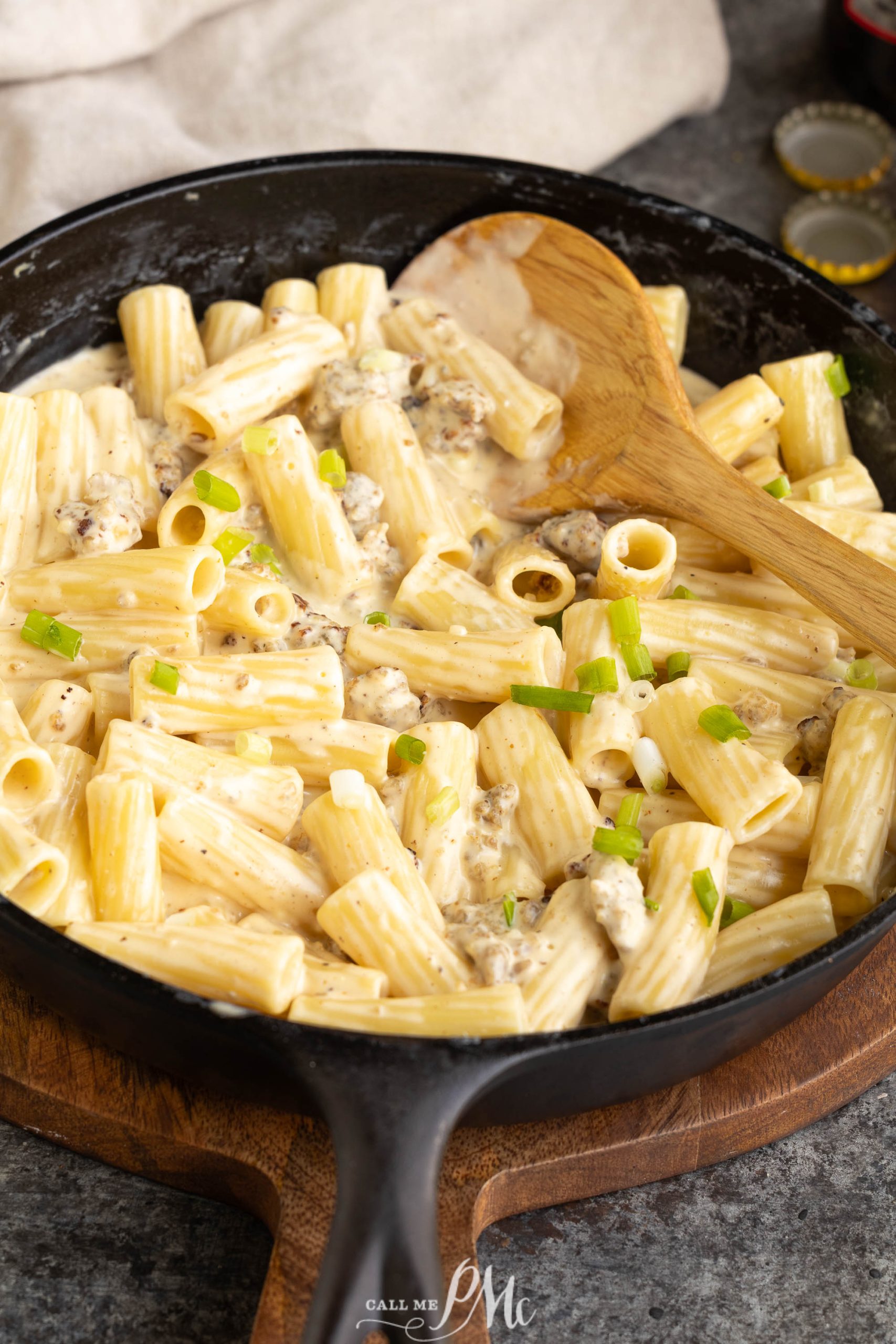 A skillet full of pasta with cheese and green onions.