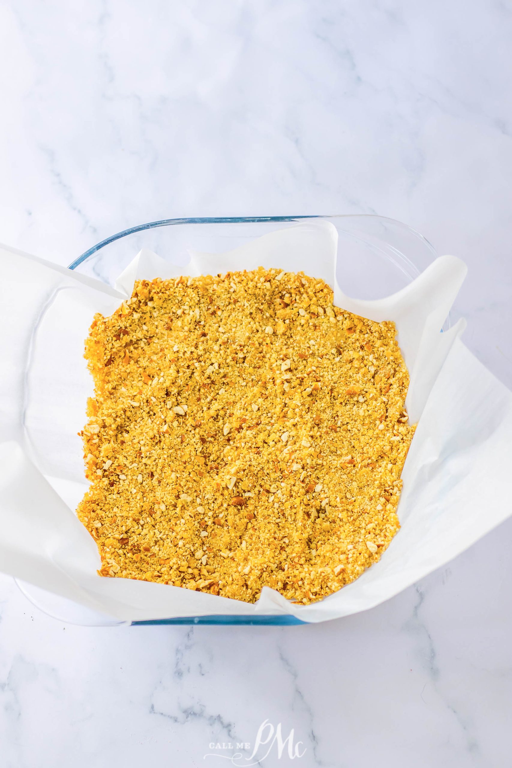 A bowl of granola in a glass on a marble counter.