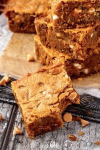 A stack of pumpkin brownies on a cutting board.
