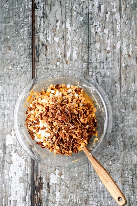 A bowl full of granola and nuts on a wooden table.